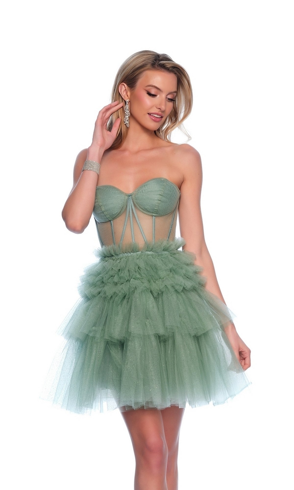 A woman poses with one hand near her face, wearing the Dave & Johnny Short Green Ruffle Hoco Dress 11826, featuring a strapless corset-style bodice, sheer panels, and a layered ruffle skirt.